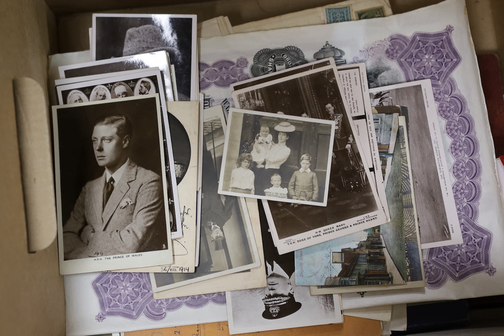 Assorted ephemera, stamps, postcard portraits of royalty, books of political cartoons, share certificates